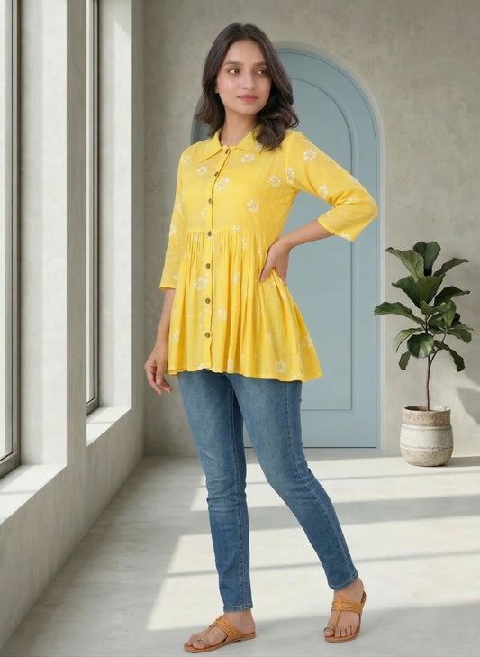 Woman wearing a yellow top and blue jeans indoors.