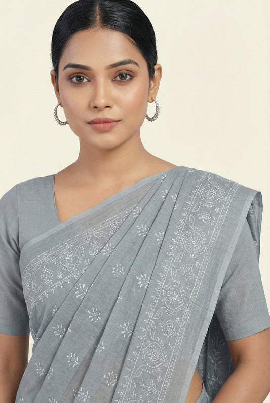 Woman wearing a gray saree with a subtle pattern on a plain background
