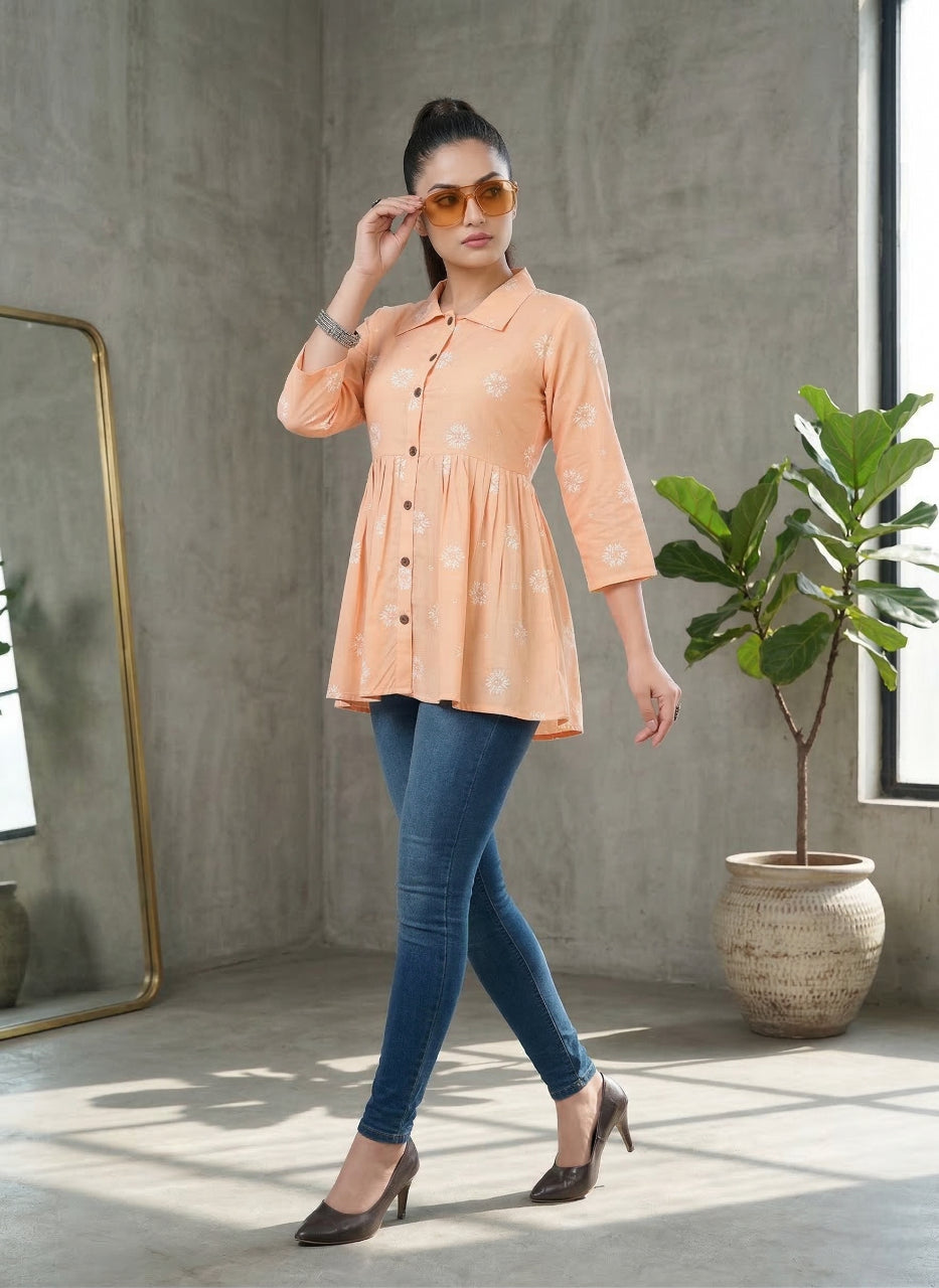 Woman wearing a peach blouse and blue jeans standing in a room with a plant and mirror.
