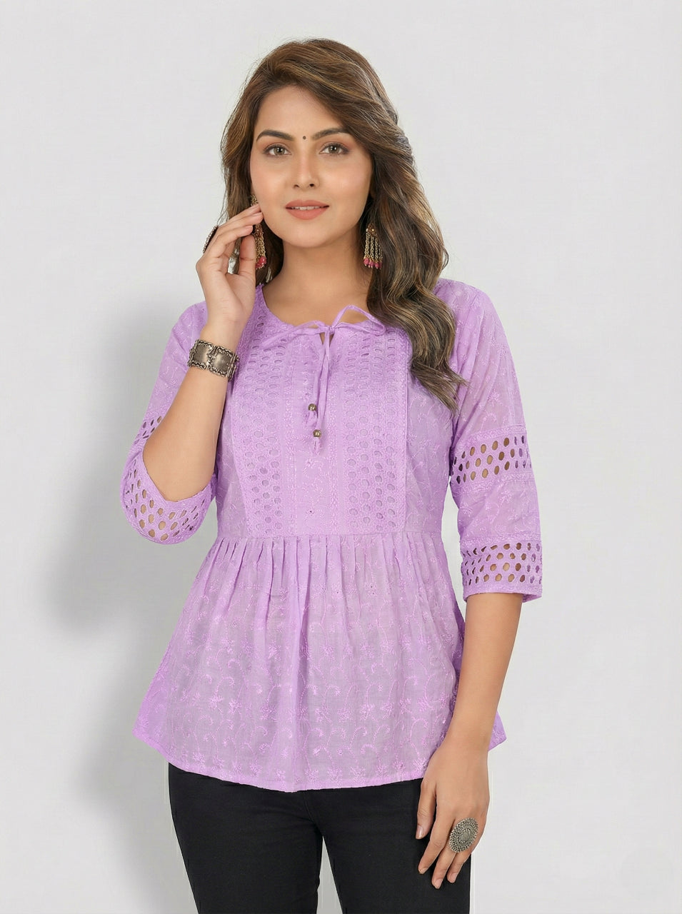 Woman wearing a purple top with lace details on a white background