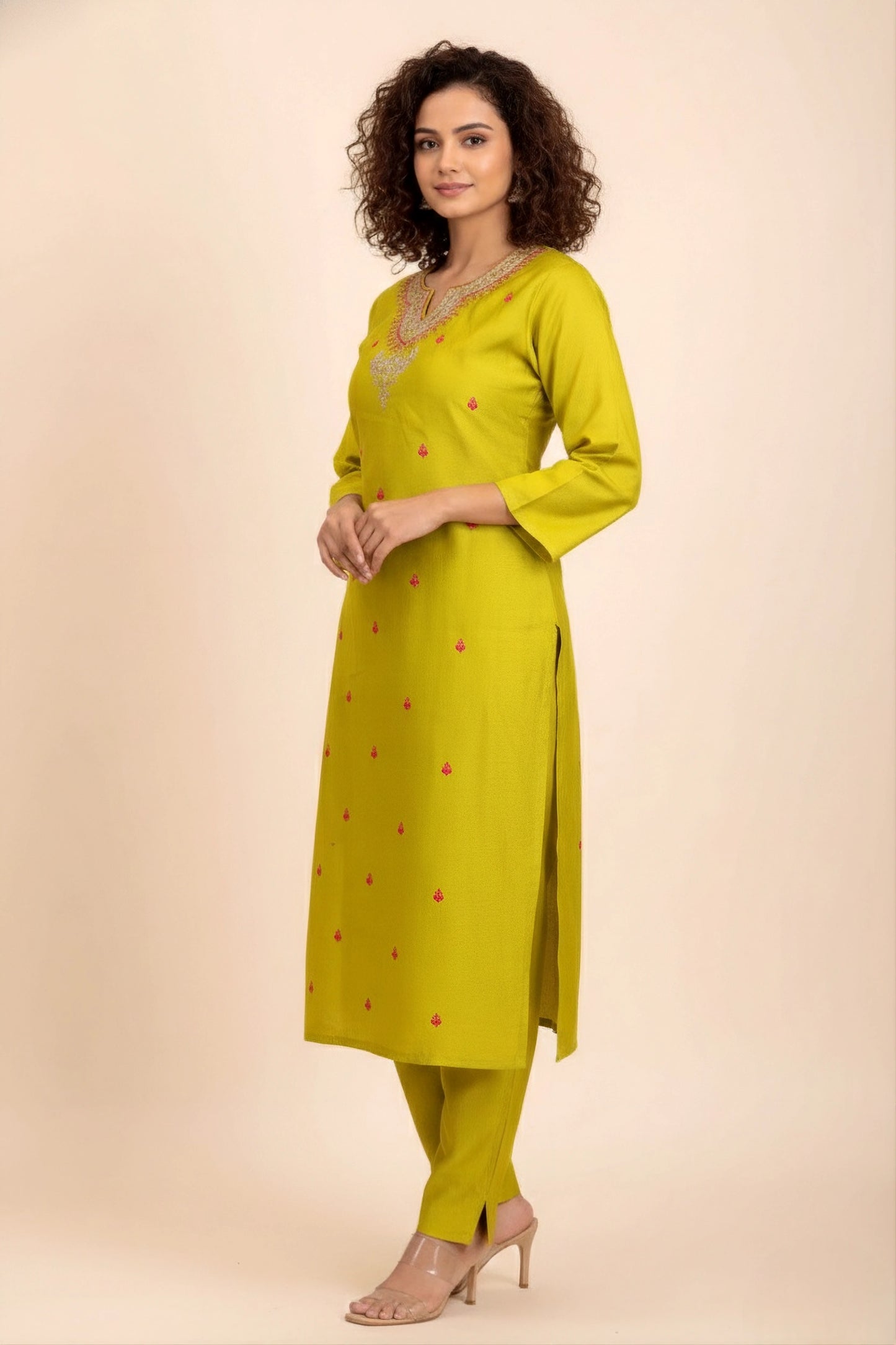 Woman wearing a yellow kurta with red patterns on a beige background
