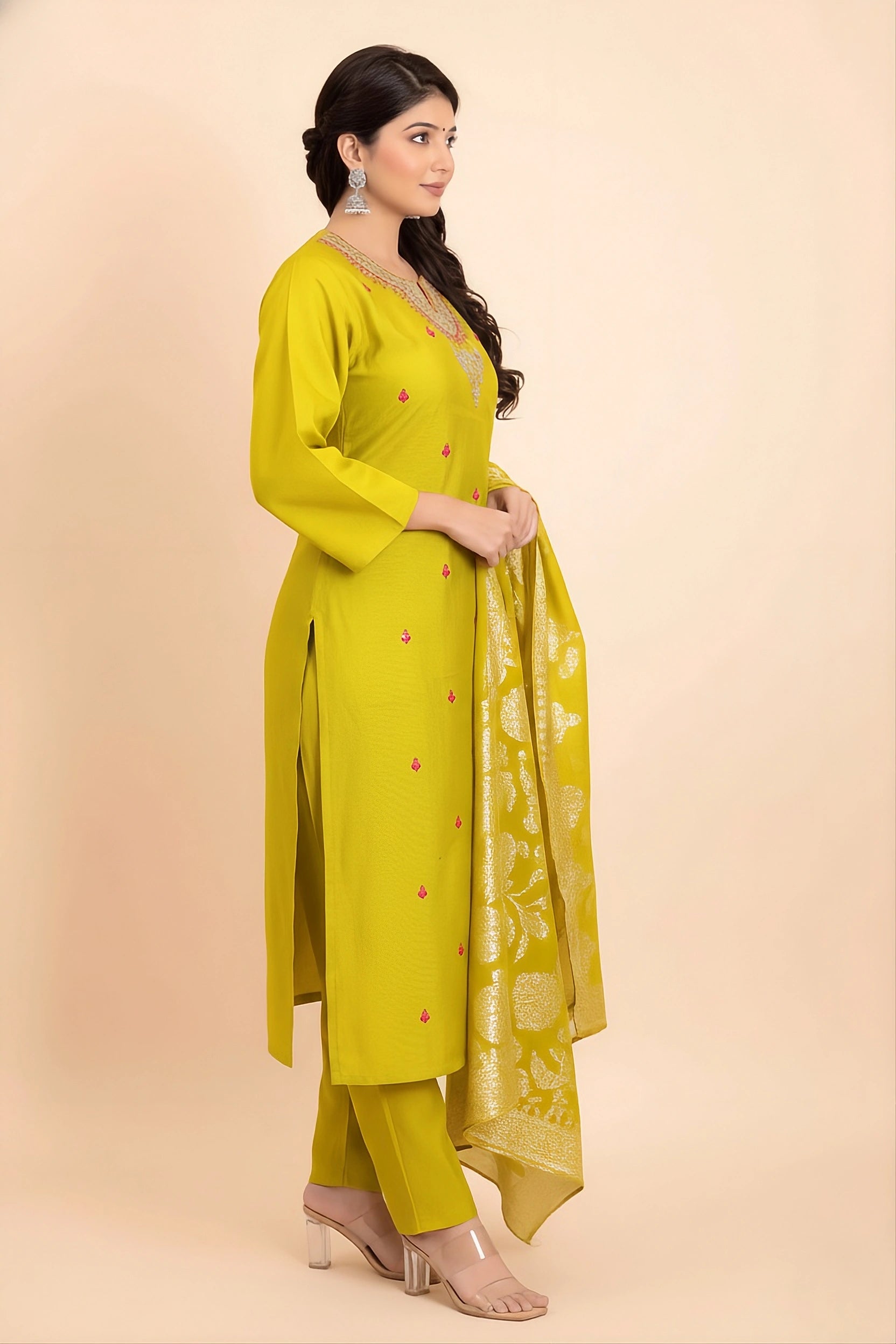 Woman wearing a bright yellow traditional outfit with a dupatta on a beige background